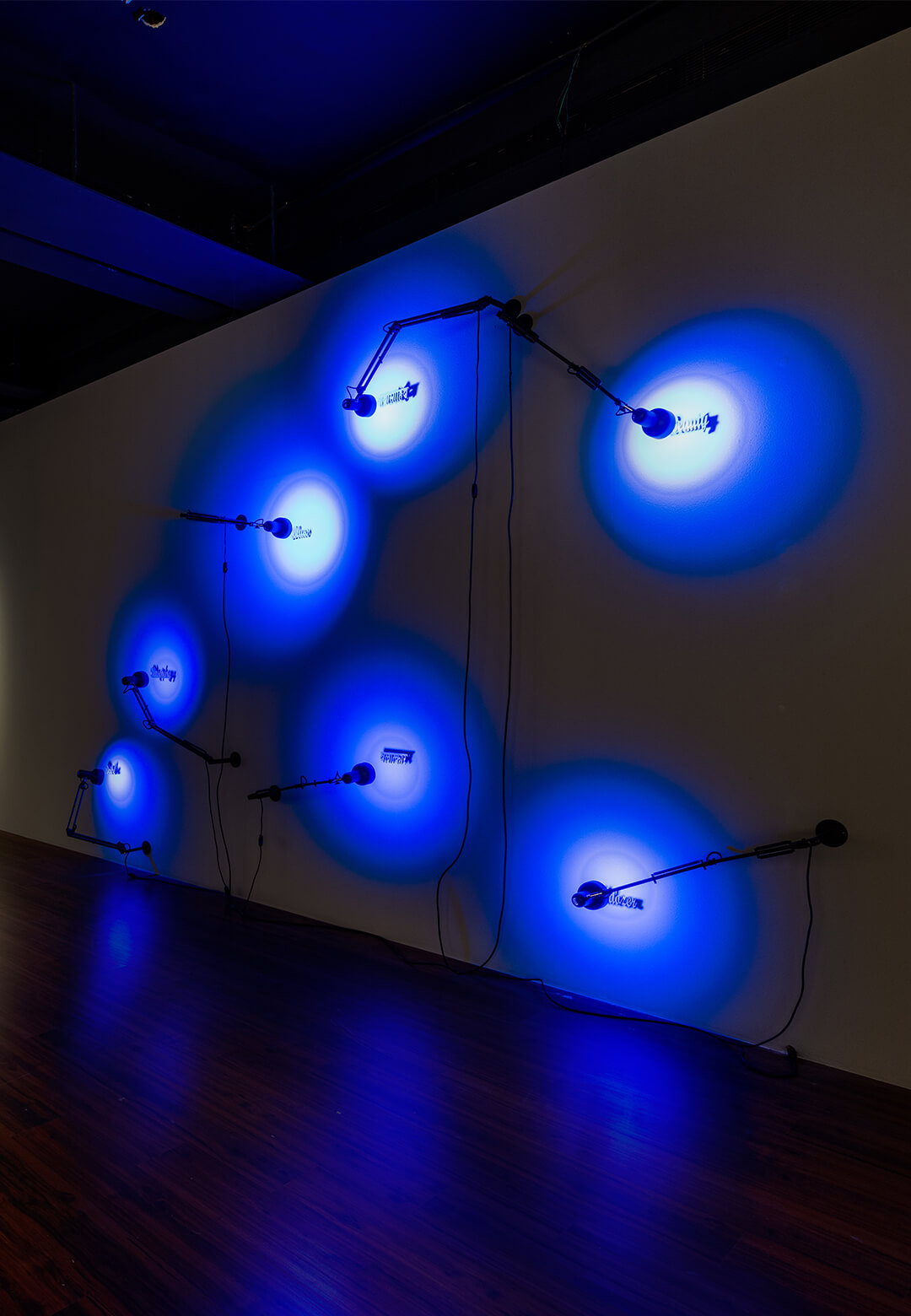 Installation view of Prussian Blue, 2023, (L) Sewed Ceiling, Textile and Prussian blue pigments, 2023, Alke Reeh; (R) Thinking through Prussian Blue, Seven steel words, seven steel lamps, bulb, and wi