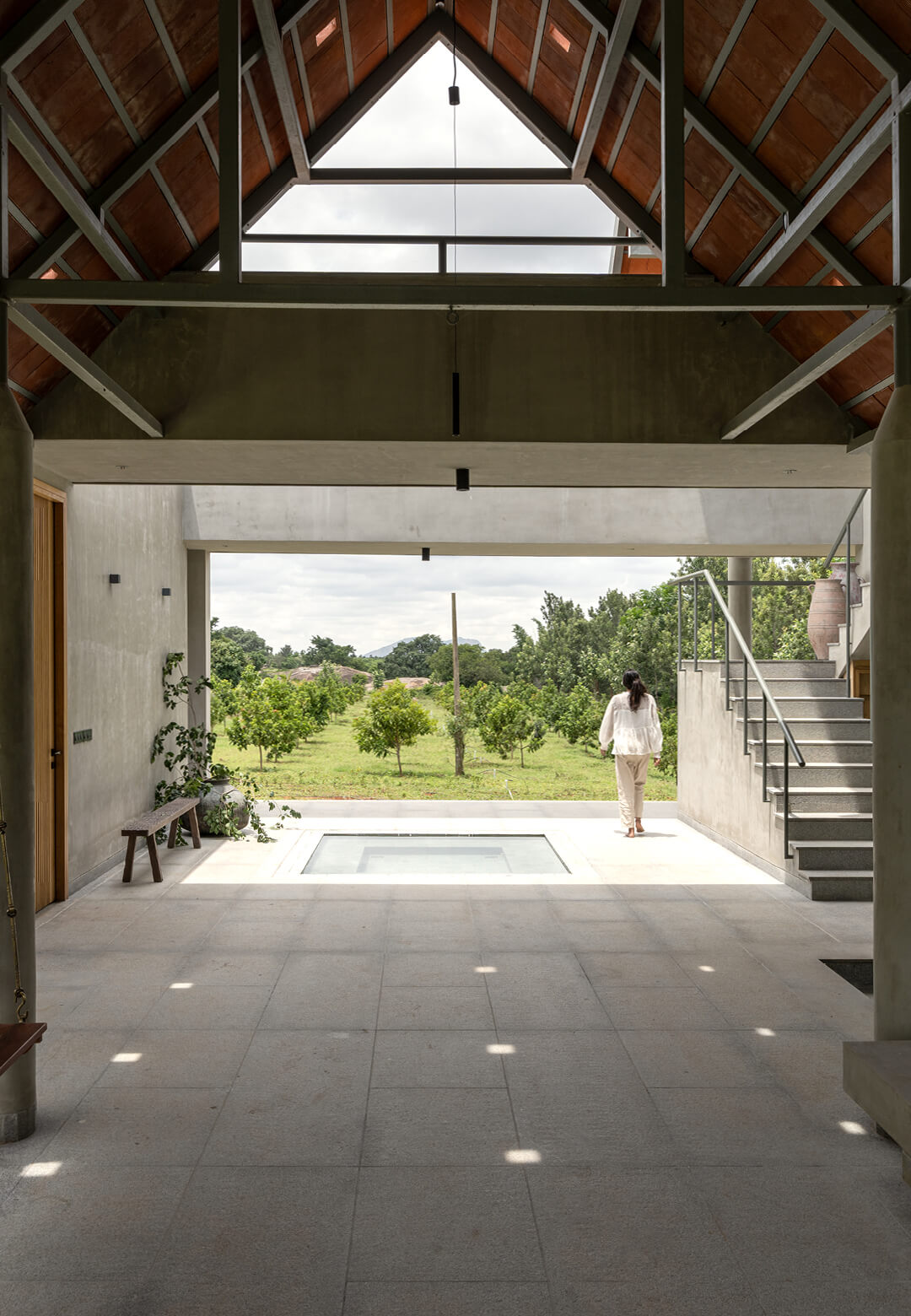 Set within a two-acre plot in rural Karnataka, the house designed by Taliesyn is defined by mature trees and exposed boulders that were retained as part of the residential design | House by the Grove